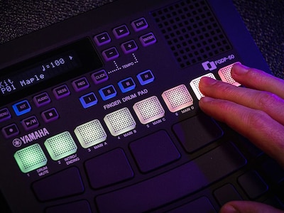 Close-up of fingers touching the glowing RGB pads on the FGDP-50