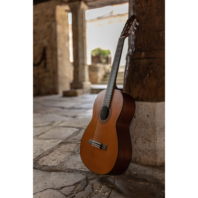 Solid cedar top CGX122MC guitar leaning on a column in an outdoor plaza in Pedraza, Segovia