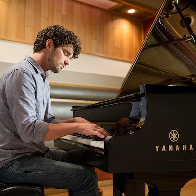 Image of a man playing acoustic piano