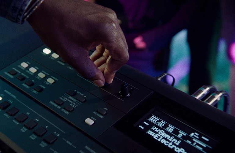 Hand turning the knob of a synthesizer