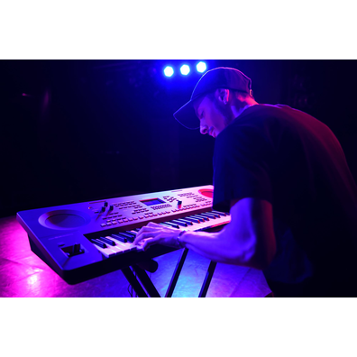 A person playing a Yamaha arranger workstation on a stand under stage lighting