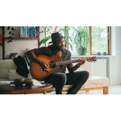 Man sitting indoors playing the TAG3 C acoustic guitar.