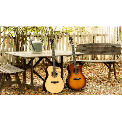 Two acoustic guitars resting by a wooden bench outdoors.