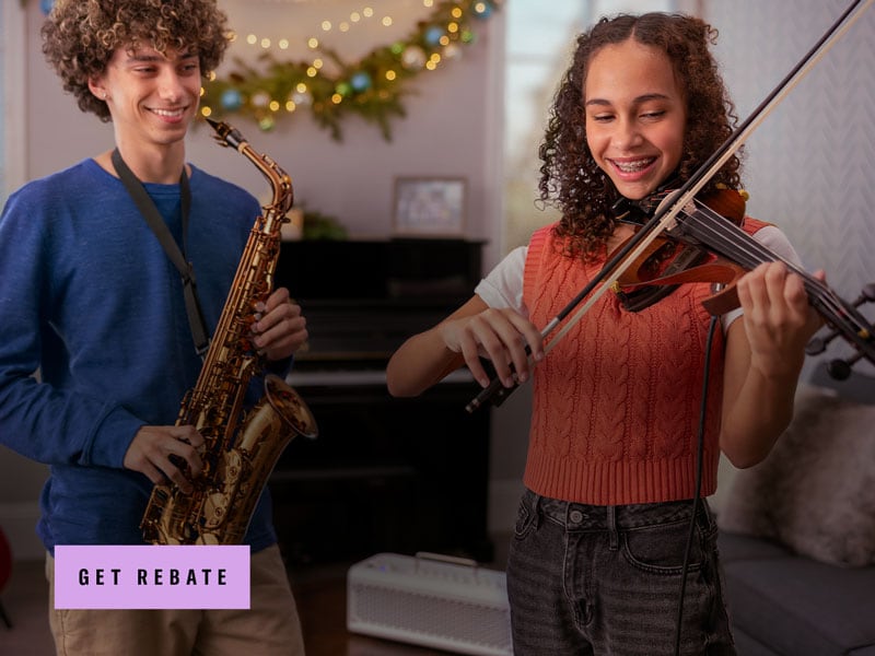 Teenager boy smiling holding the saxophone and girl smiling playing the violin 