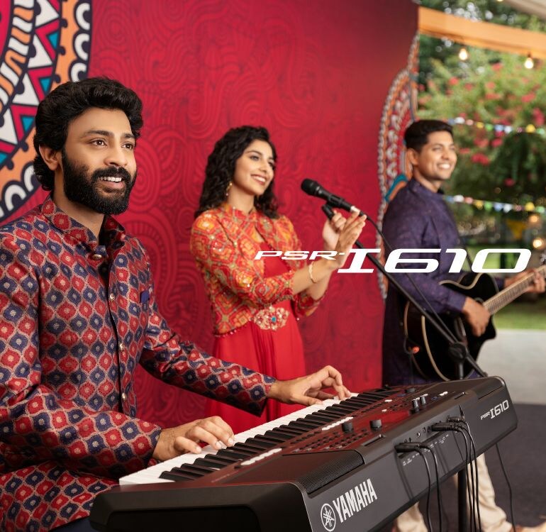 A vocalist, a guitarist, and a performer using the PSR-I610, play as a band outdoors