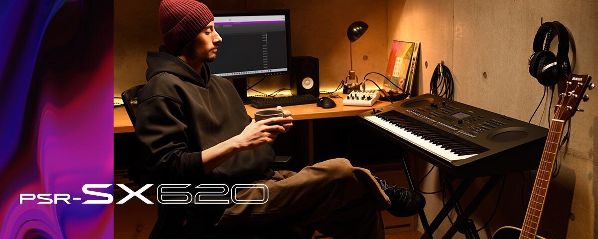 Person sitting at a PSR-SX keyboard in a home studio, drinking coffee.