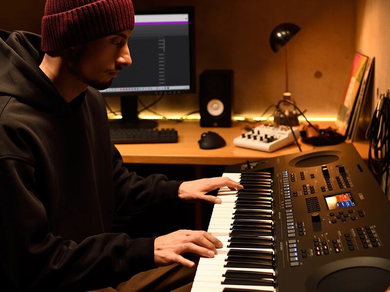 Person playing a PSR-SX620 keyboard in a home studio.