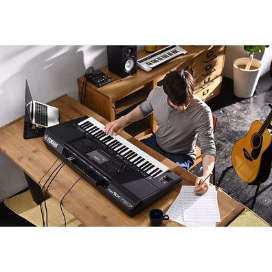 Photo of a person writing on sheet music while playing the Yamaha Arranger Workstation PSR-SX720+