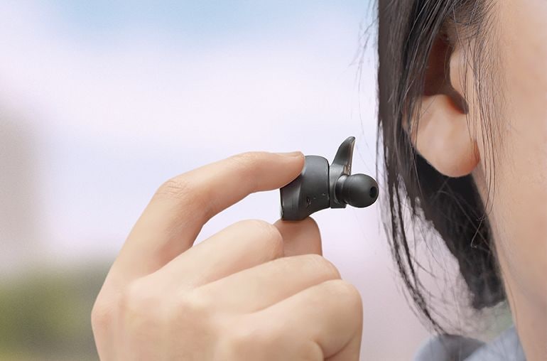 Lifestyle image of a person removing TW-ES5A earbuds from ear