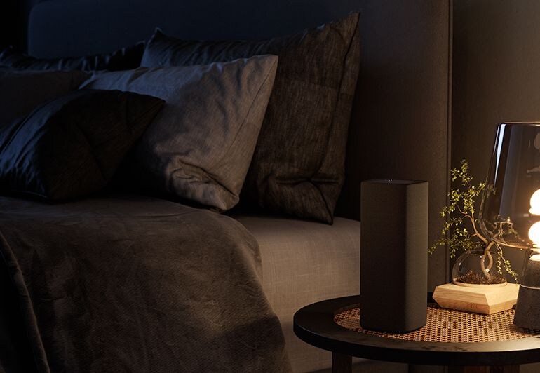 The True X speakers featured in a bedroom beside the lamp