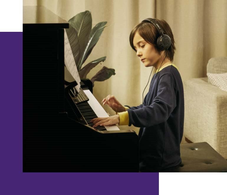 Image of a boy playing Yamaha digital piano wearing headphone