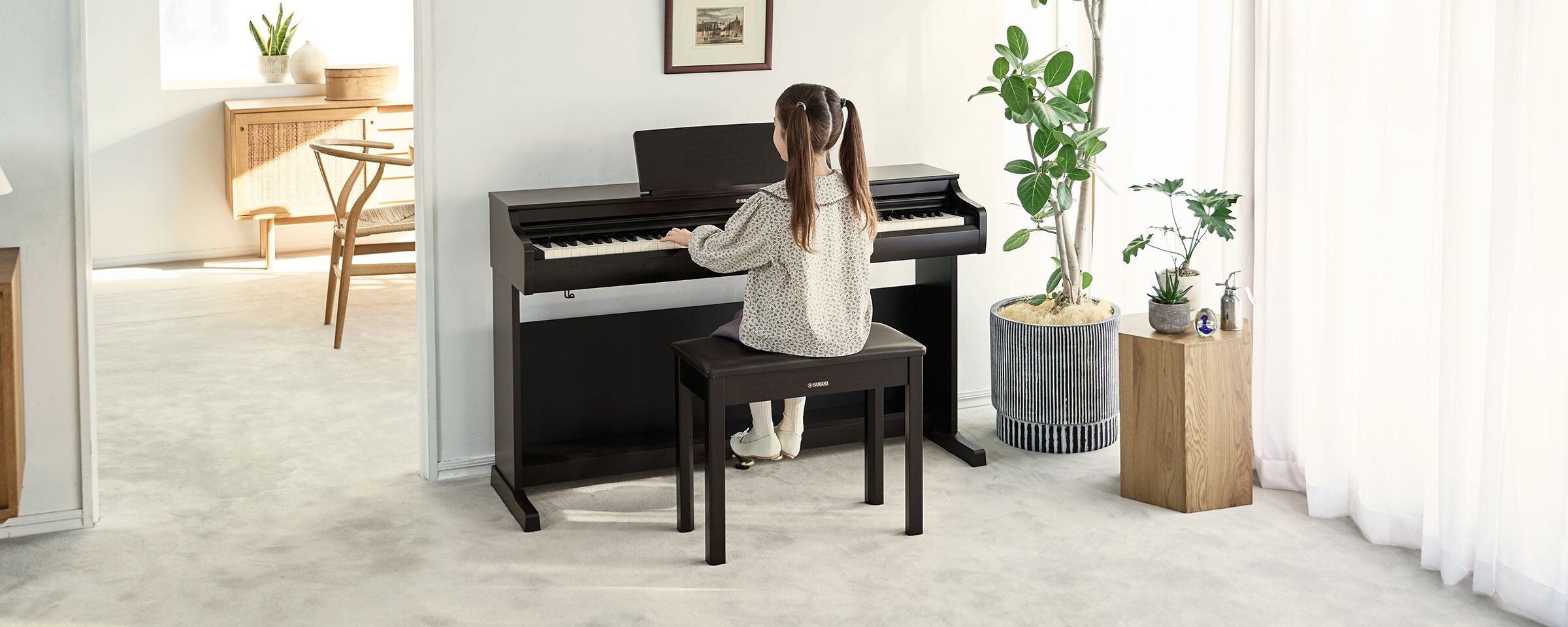 A young girl practicing on an ARIUS piano in a living room