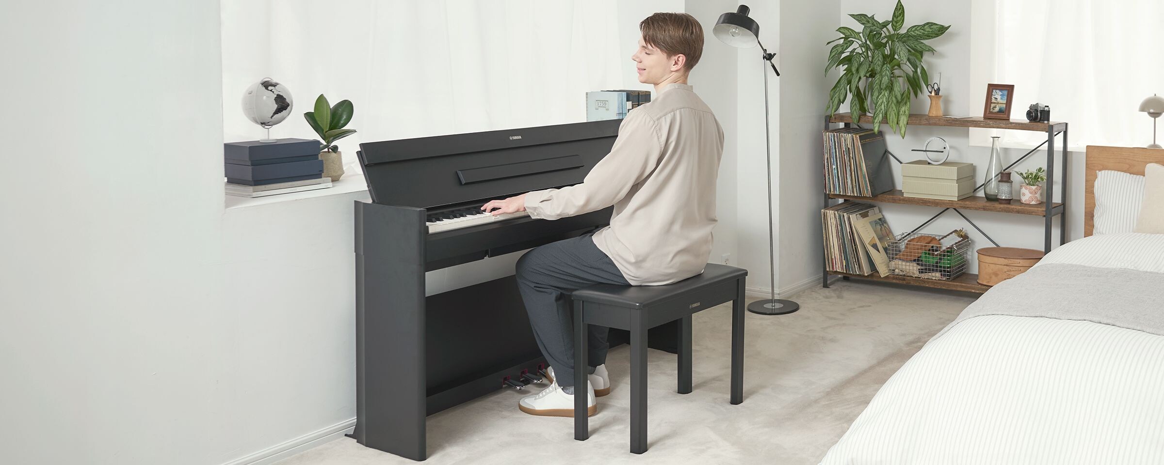 A man playing an ARIUS piano in a bedroom in a relaxed setting