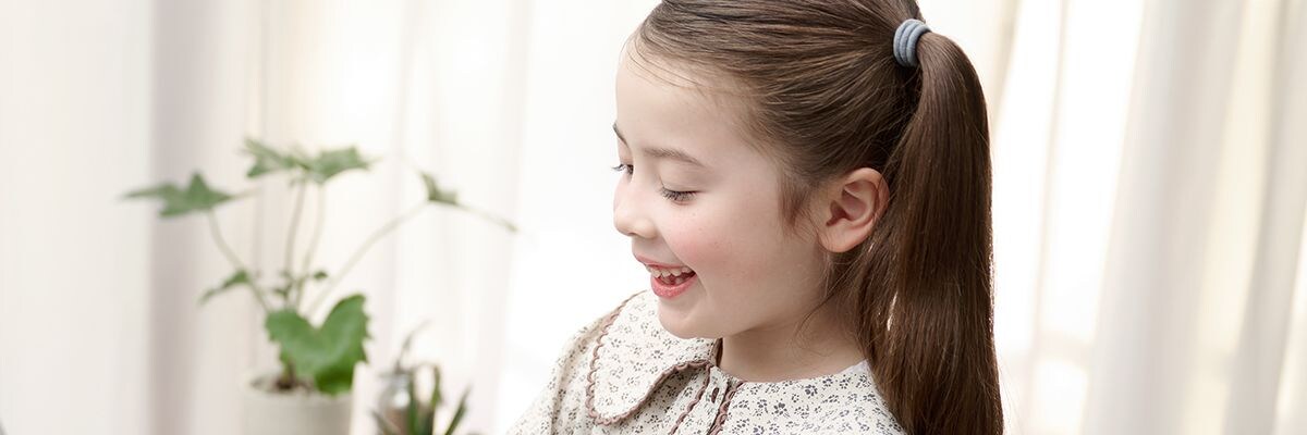 The side profile of a young girl happily playing an ARIUS piano
