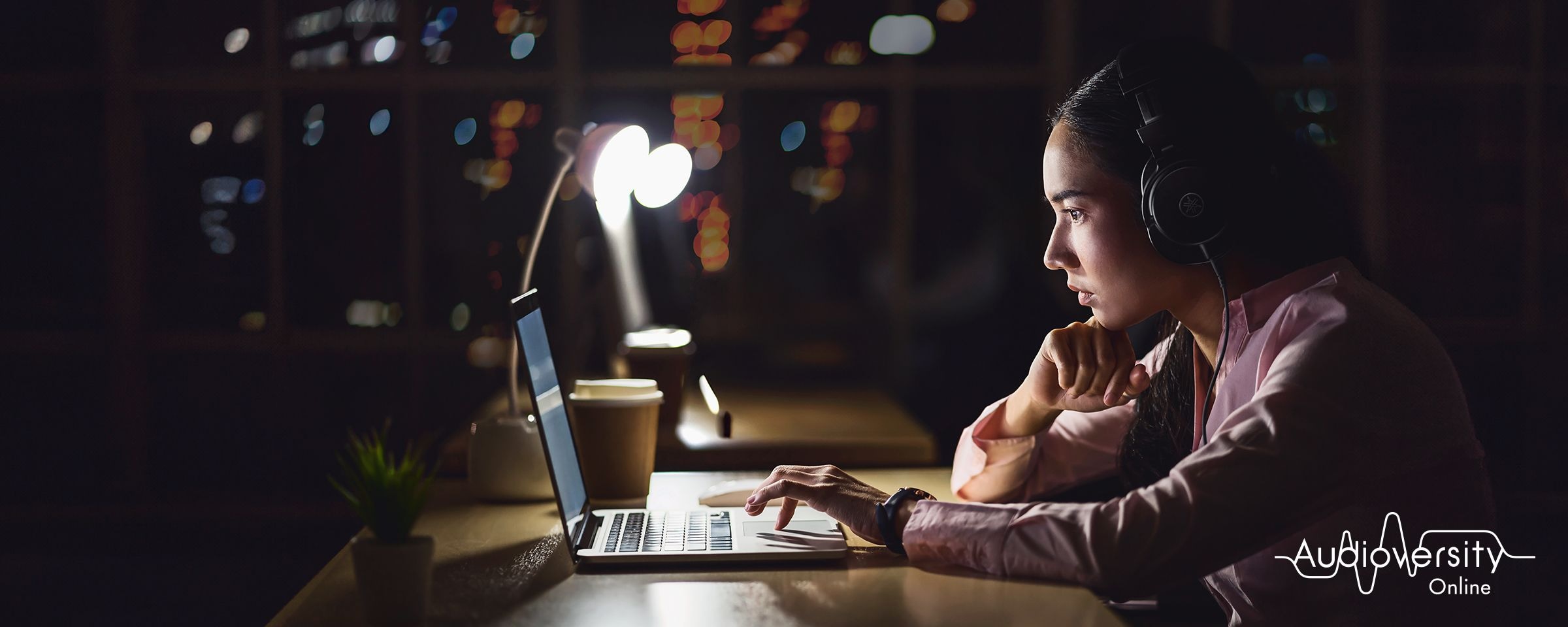 Key visual for Audioversity Online: a woman focused on an online training session.