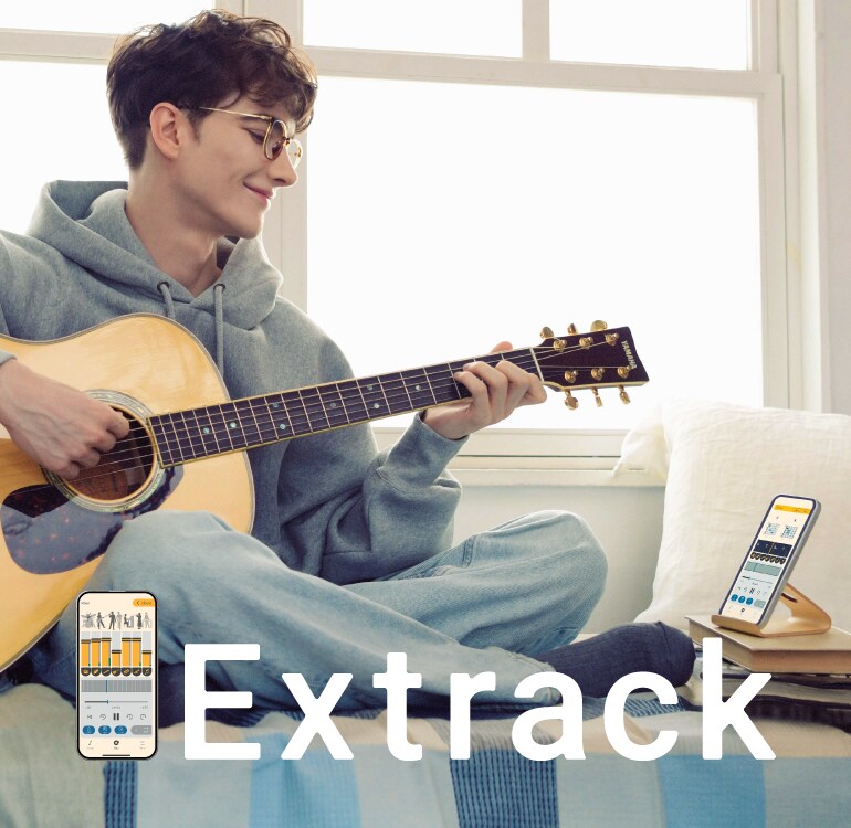 A man enjoys practicing the guitar while sitting on the sofa and playing along with the Extrack music practice app