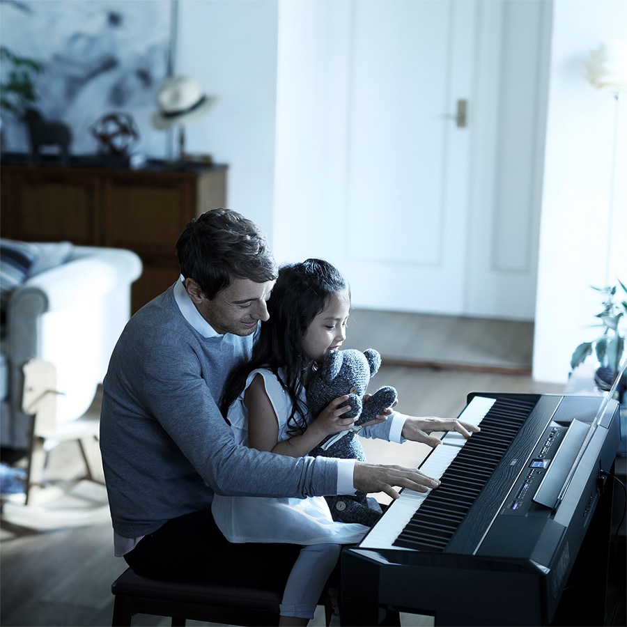 father and daughter playing p-515 piano in a living room