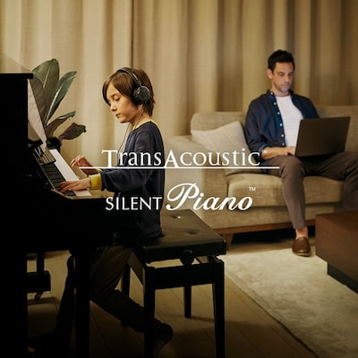 Image showing a young boy playing transacoustic piano wearing a headphone and a man is shown with laptop sitting on sofa